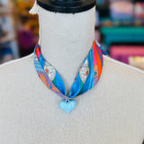 Blue printed scarf necklace featuring a glossy baby blue heart charm; playful and lightweight accessory perfect for adding color and charm to any outfit.