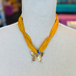Gold print scarf necklace featuring a delicate gold butterfly charm; a whimsical and stylish accessory perfect for adding elegance and playful charm to any outfit.