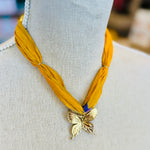 Gold print scarf necklace featuring a delicate gold butterfly charm; a whimsical and stylish accessory perfect for adding elegance and playful charm to any outfit.