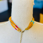 Gold print scarf necklace featuring a delicate gold butterfly charm; a whimsical and stylish accessory perfect for adding elegance and playful charm to any outfit.