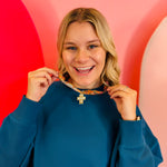 Patterned scarf necklace with a sculpted gold cross charm and crystal accents, blending vintage style with modern elegance