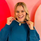 Patterned scarf necklace with a sculpted gold cross charm and crystal accents, blending vintage style with modern elegance