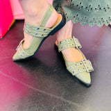 Olive pointed-toe flats with bold silver double buckle straps and a slingback backstrap, combining vibrant color with edgy charm.