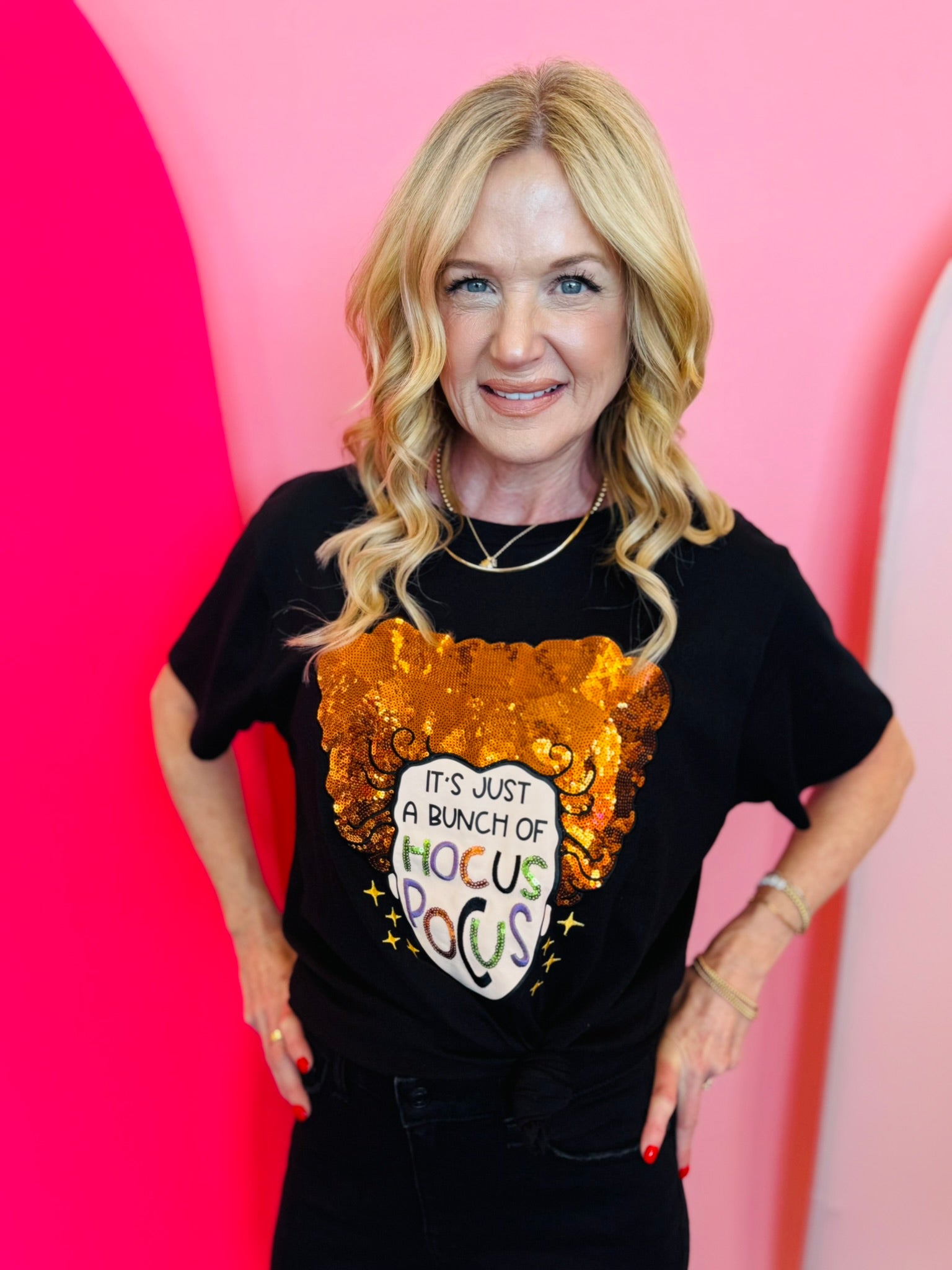 A black crewneck t-shirt featuring a glittery orange witch hat graphic. Below the hat, the text reads, "It's Just a Bunch of Hocus Pocus" in a stylized font.