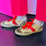 Leopard suede sneakers with red stripe, red laces, and gold heel accent.