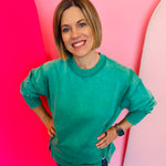 A relaxed-fit, kelly green acid wash fleece sweatshirt. The sweatshirt has visible exposed seams and a side slit at the bottom.