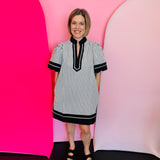 Black and white striped mini dress with lantern sleeves, caftan neckline, and contrast trim.