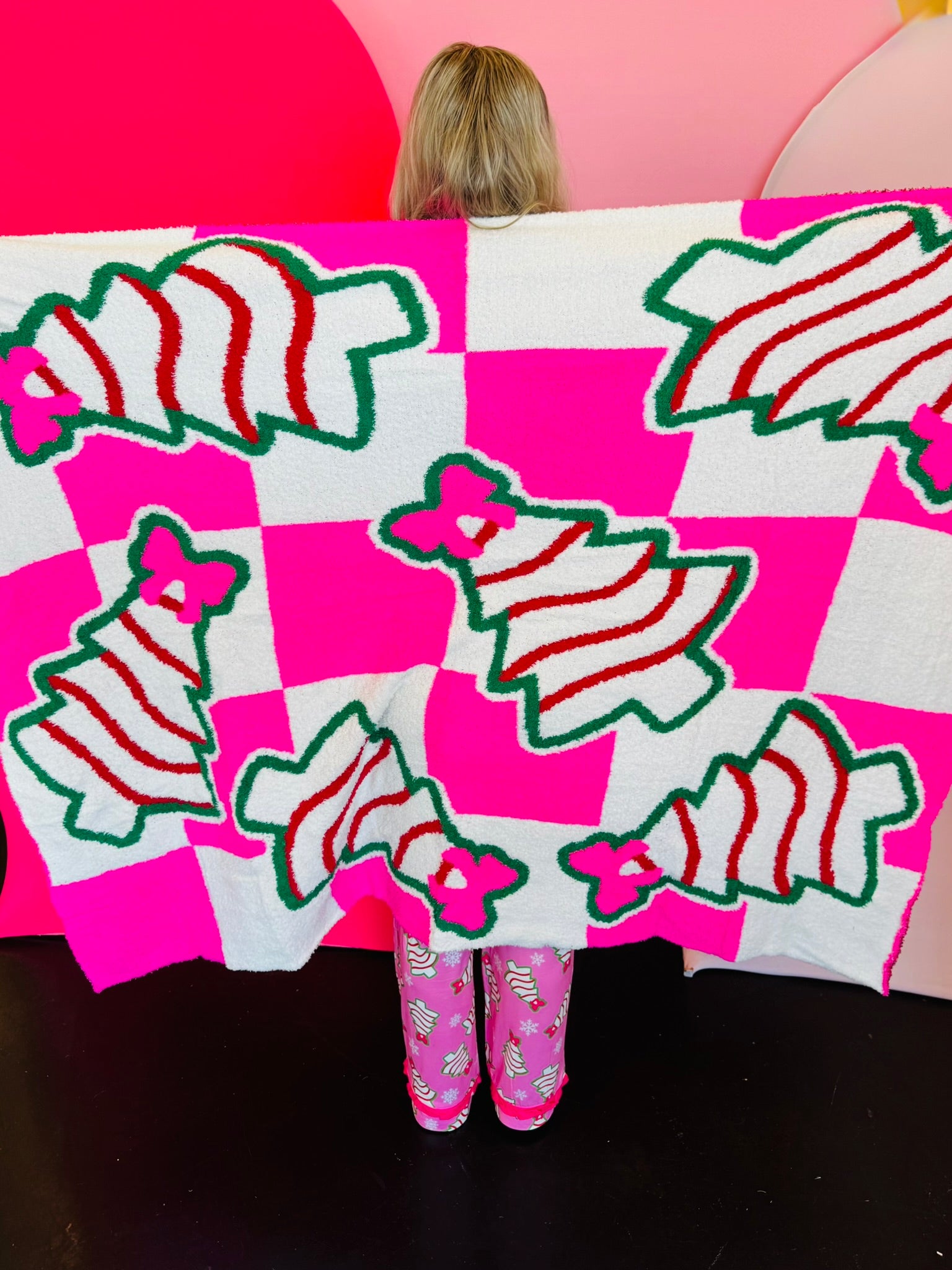 Pink checkered blanket with Christmas treats and pink bow design.