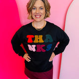 Colorful chenille  lettering that states “thanks” on a black pullover