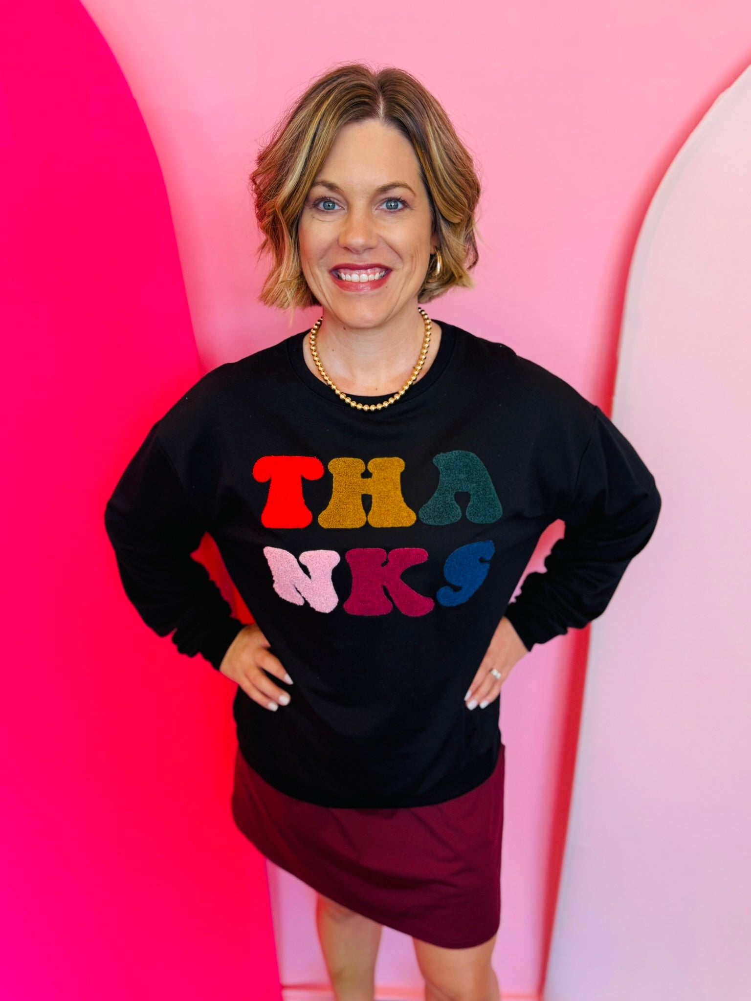 Colorful chenille  lettering that states “thanks” on a black pullover