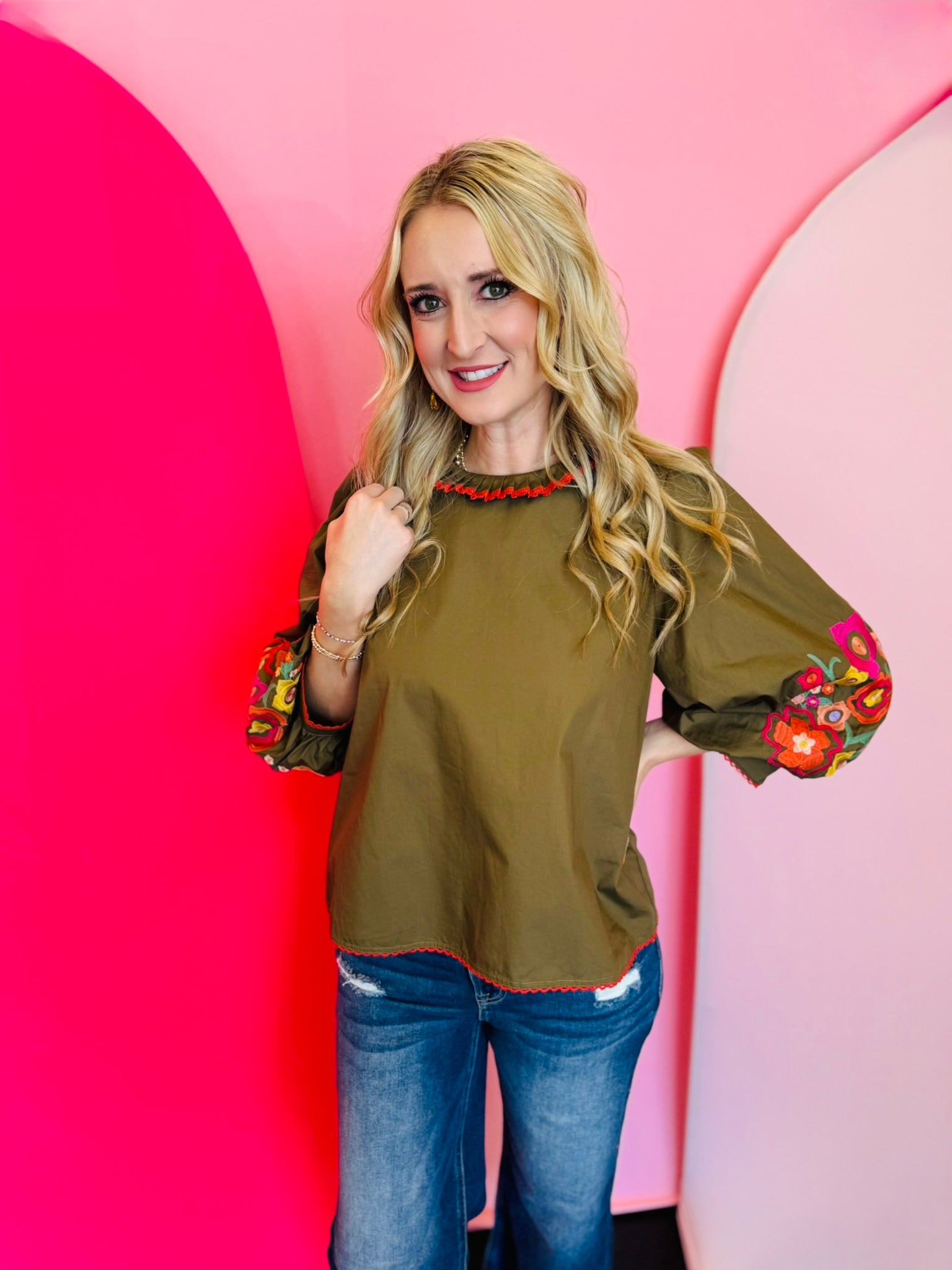 Olive embroidery top with red trim, floral sleeves, and ruffled mock neck.