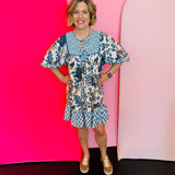 Blue floral babydoll dress with gold print, smocked detail, ruffle hem, and balloon sleeves.