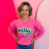 A pink sweatshirt with bold, textured green chenille lettering that spells "merry" across the chest.