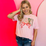 Pastel pink “Merry” sublimated Christmas tee with bow, reindeer and gingerbread men.