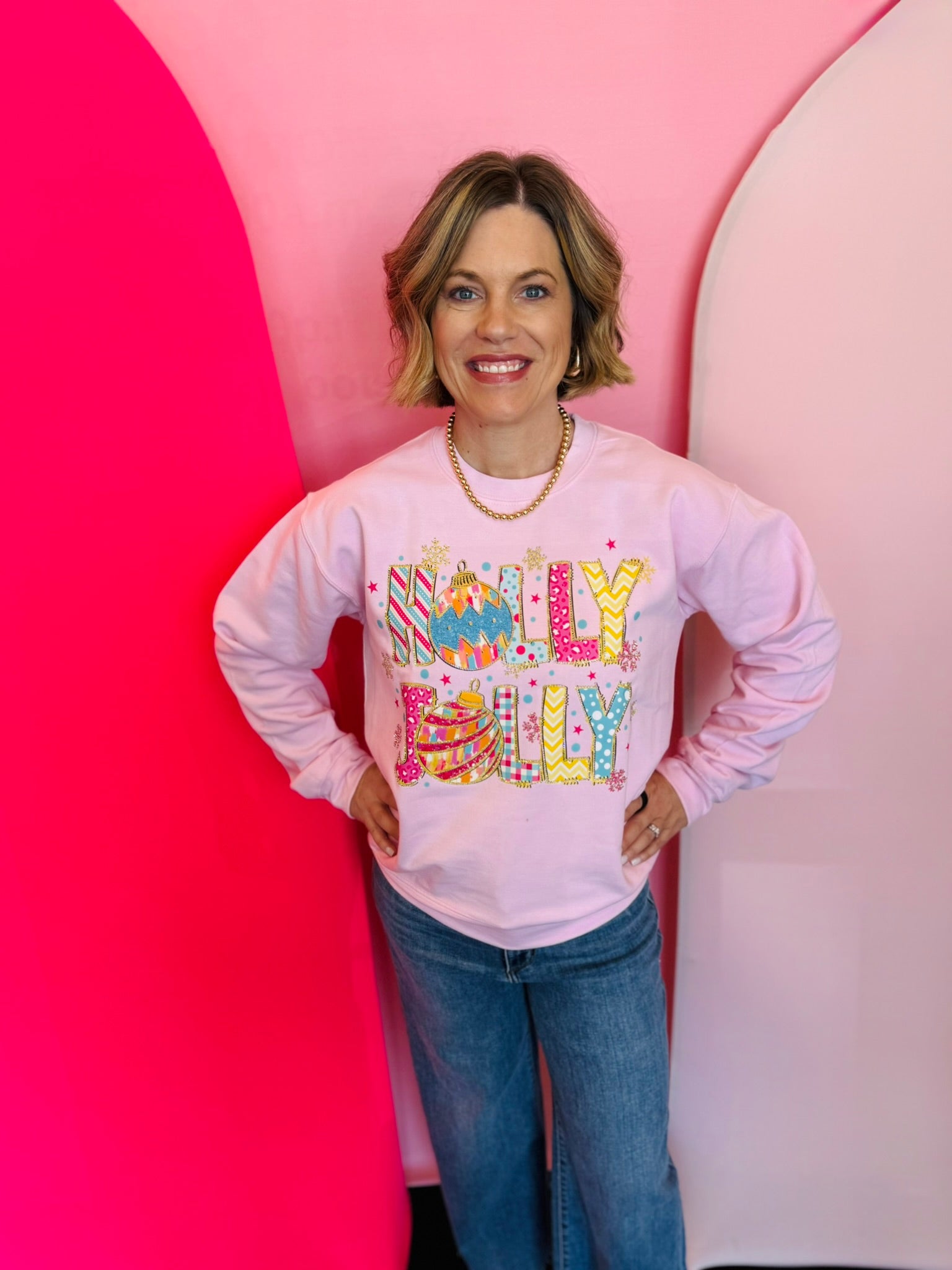 Pink Holly Jolly sweatshirt with rhinestone lettering, ornaments, and snowflake accents.