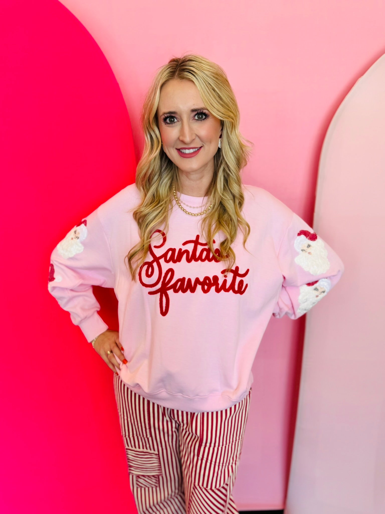 Pale pink sweatshirt with chenile Santa's Favorite lettering and sequin Santa down both sleeves.