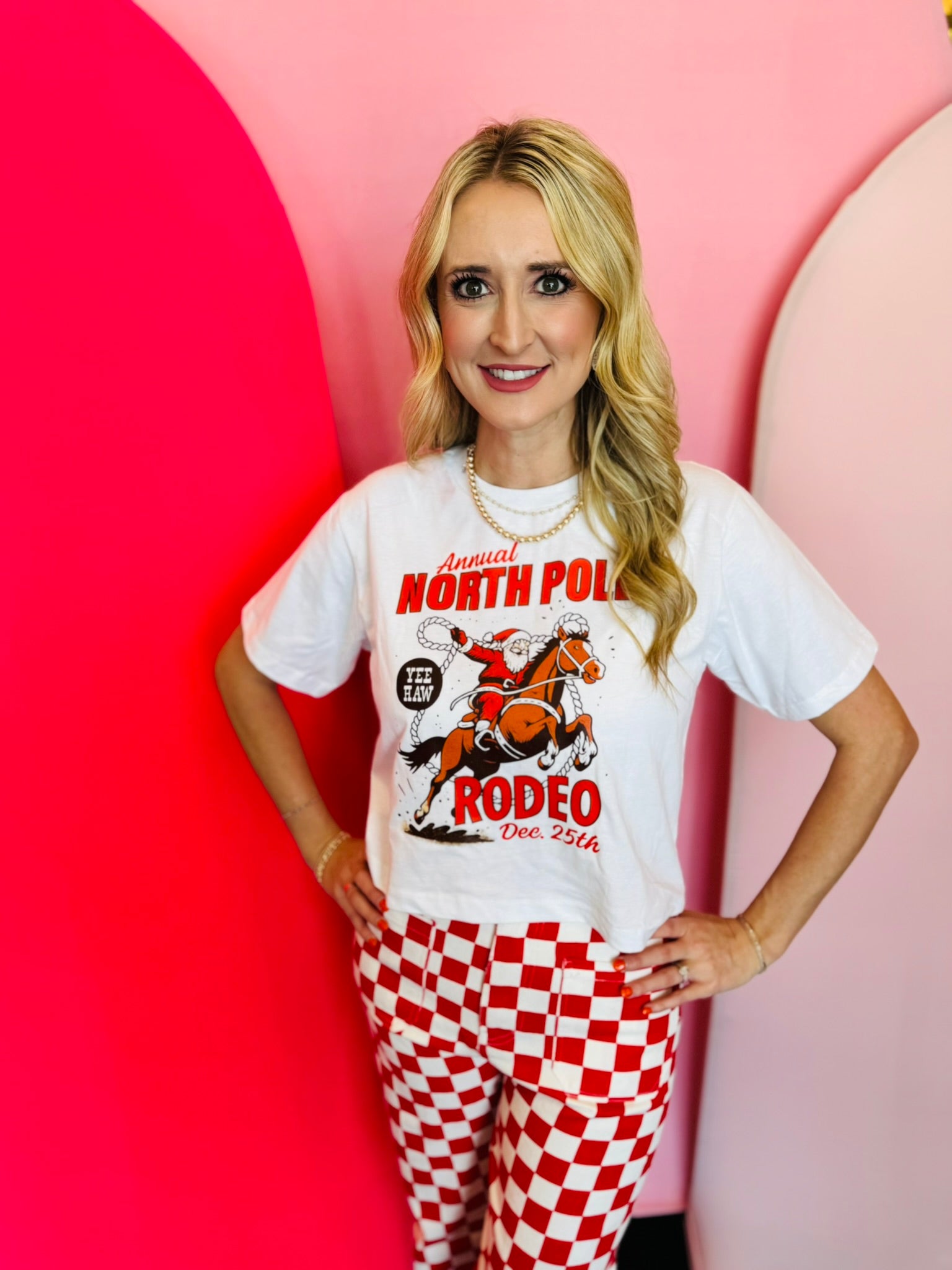 Santa rodeo graphic tee with “North Pole Rodeo” text on soft red cotton.