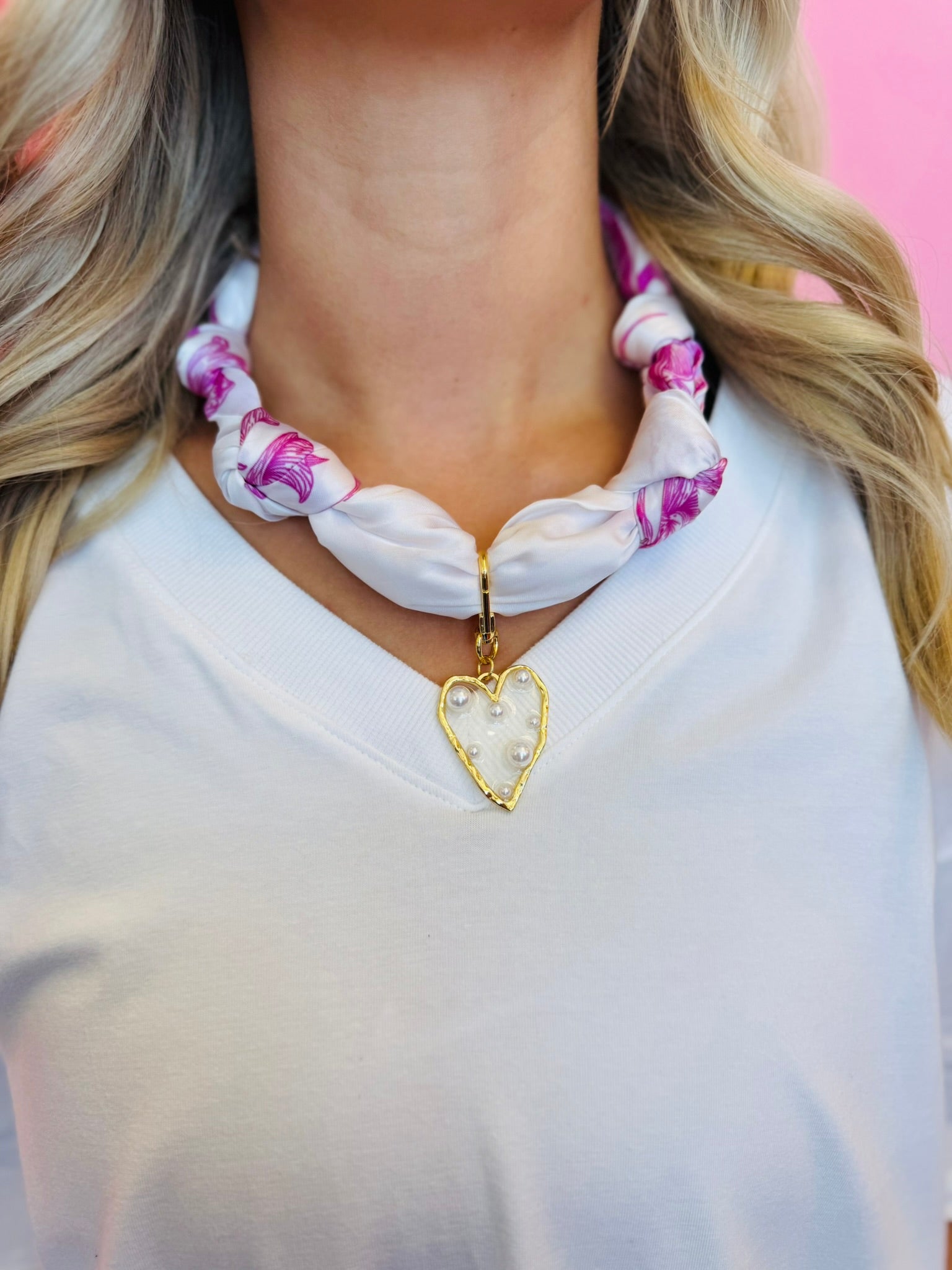 Close-up of the White & Fuchsia silky scarf necklace featuring a gold-trimmed, pearl-embellished heart charm, displayed to highlight color and detail.