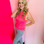 Side profile of the pink sweater vest styled with jeans, showing bold striped trim and relaxed fit.