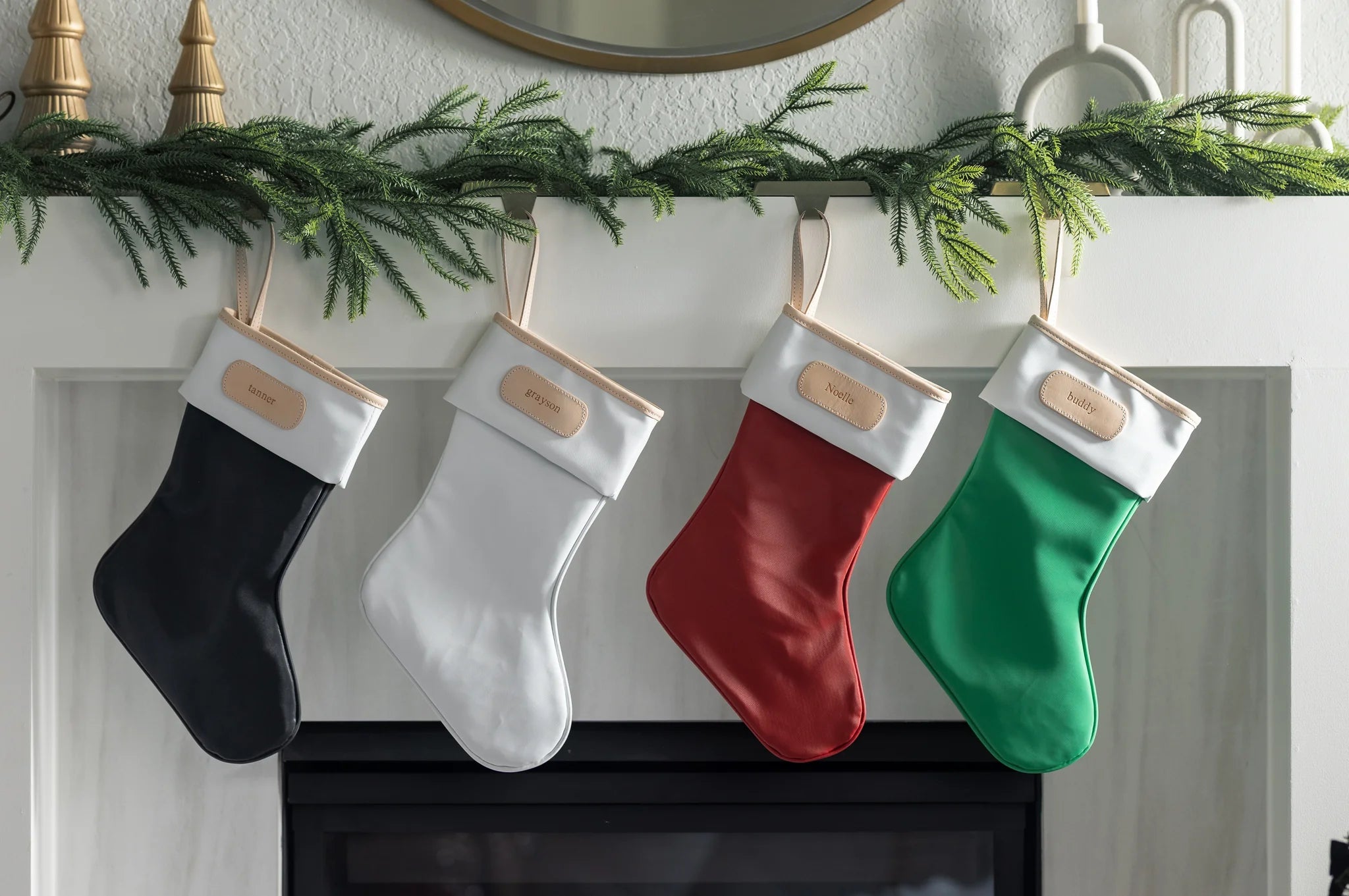 Elegant Jon Hart coated canvas holiday stocking with leather trim hanging by the fireplace