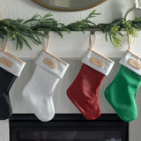 Elegant Jon Hart coated canvas holiday stocking with leather trim hanging by the fireplace