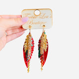 Glittery layered leaf-shaped earrings in red, green, and gold with gold chain accent and glitter gold bar.