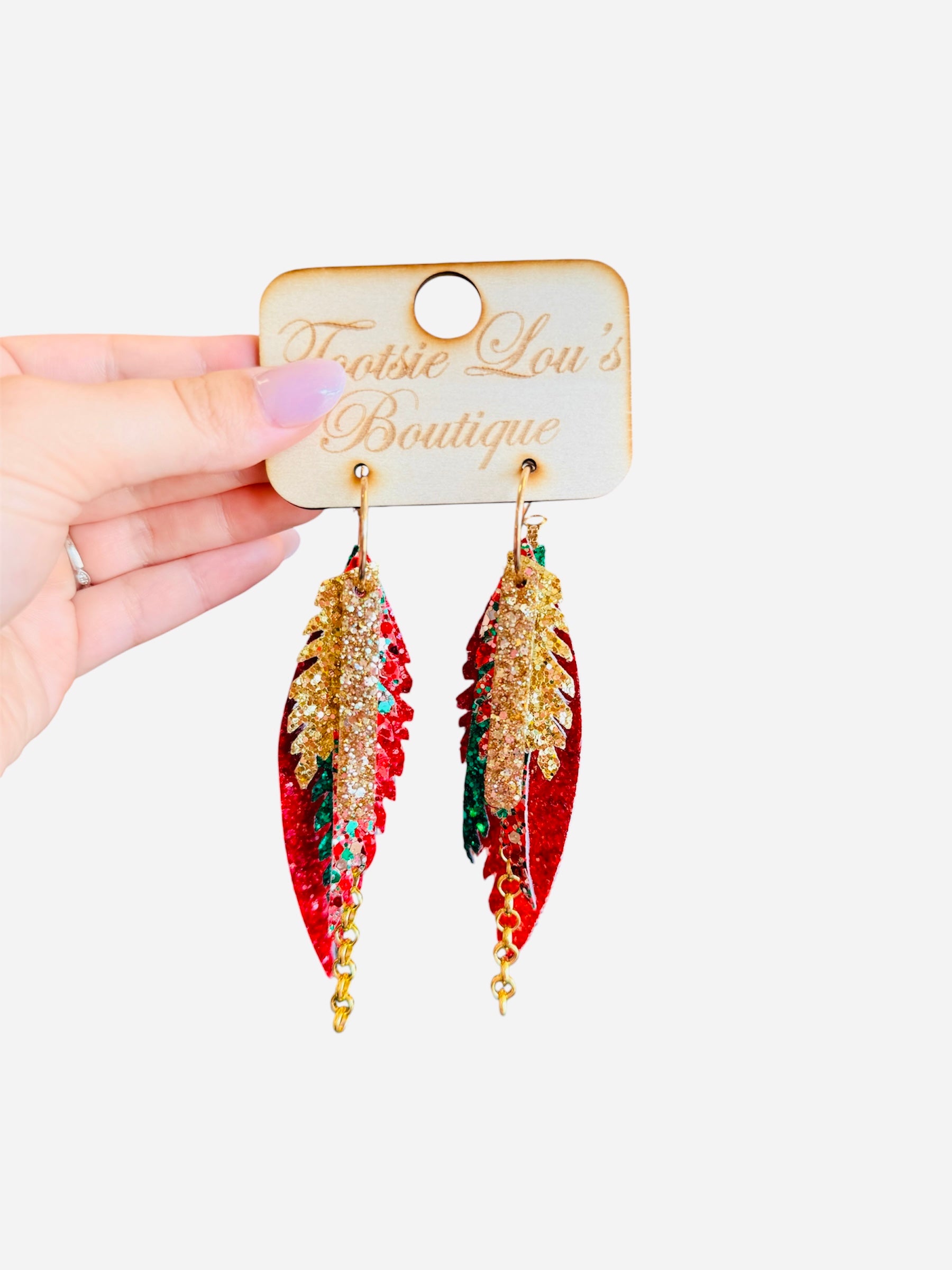 Glittery layered leaf-shaped earrings in red, green, and gold with gold chain accent and glitter gold bar.
