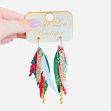 Green layered faux leather earrings with red glitter, poinsettia print, and gold chain accents.