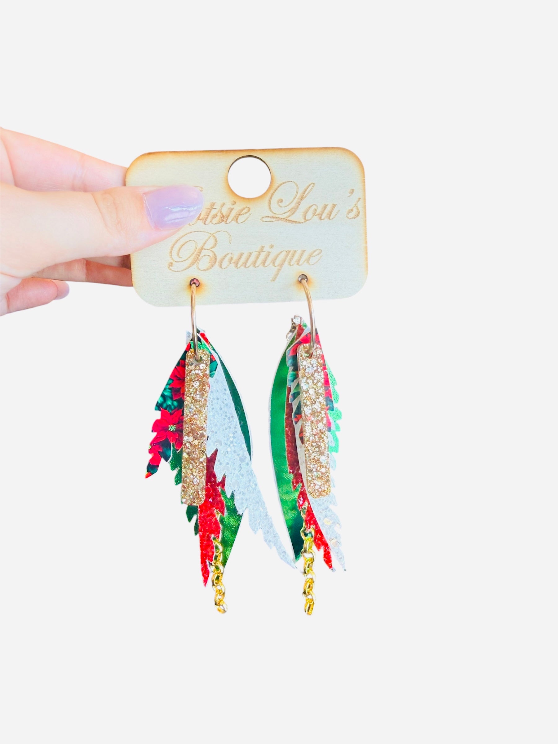 Green layered faux leather earrings with red glitter, poinsettia print, and gold chain accents.