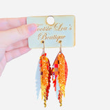 Layered feather earrings in fall colors with plaid, glitter, textured leather, and gold chain accents.