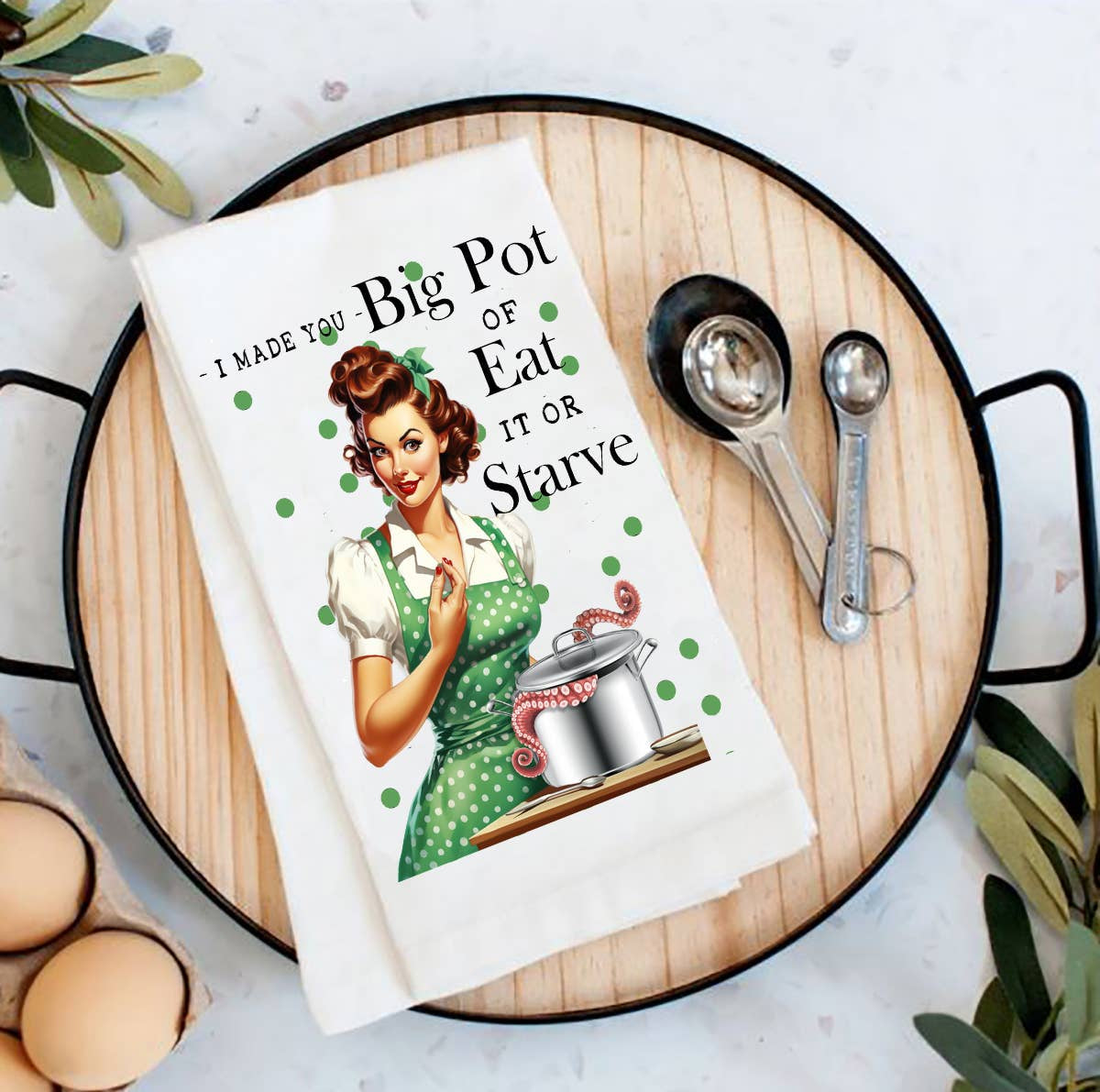 White cotton tea towel with vintage housewife and octopus pot graphic, “Eat It or Starve” quote.