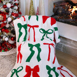 A cozy blanket featuring red and green bows on a festive background, adding holiday charm and warmth to any room.
