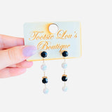 Black and pearl drop earrings linked by delicate gold chains.