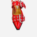 Red pointed-toe flats with bold silver double buckle straps and a slingback backstrap, combining vibrant color with edgy charm.