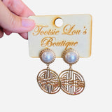 A pair of earrings featuring a central white pearl stud surrounded by a circular, textured gold medallion.
