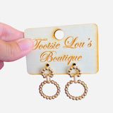 A pair of gold earrings, each featuring two interlinked hoops. Both hoops are adorned with a detailed, textured beaded pattern.