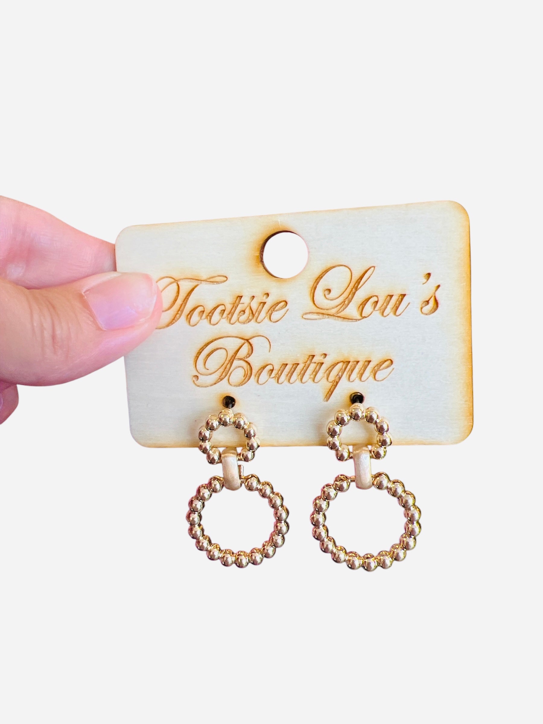 A pair of gold earrings, each featuring two interlinked hoops. Both hoops are adorned with a detailed, textured beaded pattern.