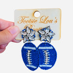 A pair of dangle earrings, each with a sparkling crystal star stud at the top. Dangling below is a football-shaped charm made from vibrant blue beads.