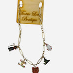 A shiny gold chain necklace featuring several dangling enamel charms, including a black cat, a white ghost, a witch hat, and a "Trick or Treat" sign.
