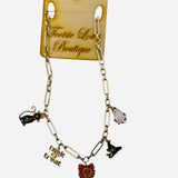 A shiny gold chain necklace featuring several dangling enamel charms, including a black cat, a white ghost, a witch hat, and a "Trick or Treat" sign.