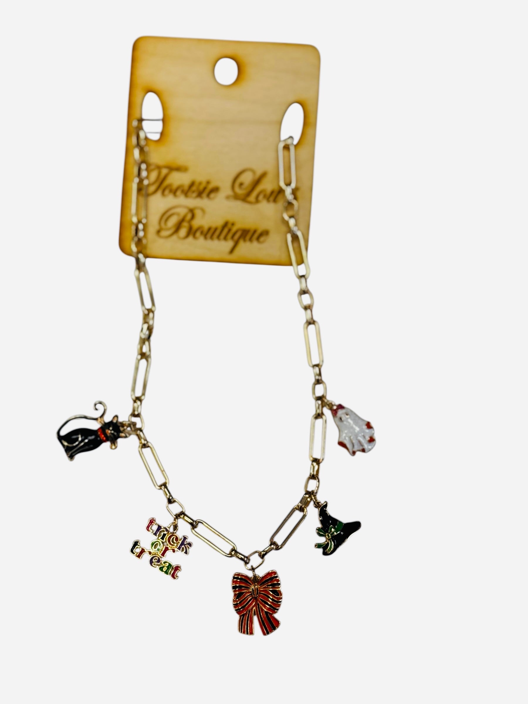A shiny gold chain necklace featuring several dangling enamel charms, including a black cat, a white ghost, a witch hat, and a "Trick or Treat" sign.