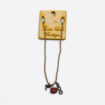 A gold ball bead chain necklace featuring three dangling charms: a glittery orange pumpkin, a black spider, and a charm that spells out the word "BOO."