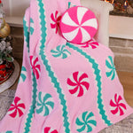 Soft pink blanket with peppermint candy designs, perfect for cozying up and adding festive charm to your holiday décor.