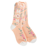 A pair of fuzzy, plush, peach-colored crew socks. The socks have small floral embroidery, and the word "MOM" is stitched across the front in a contrasting color.
