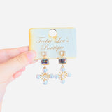 Elegant rhinestone earrings with round, rectangular, and snowflake-inspired design with square and pearl rhinestones.