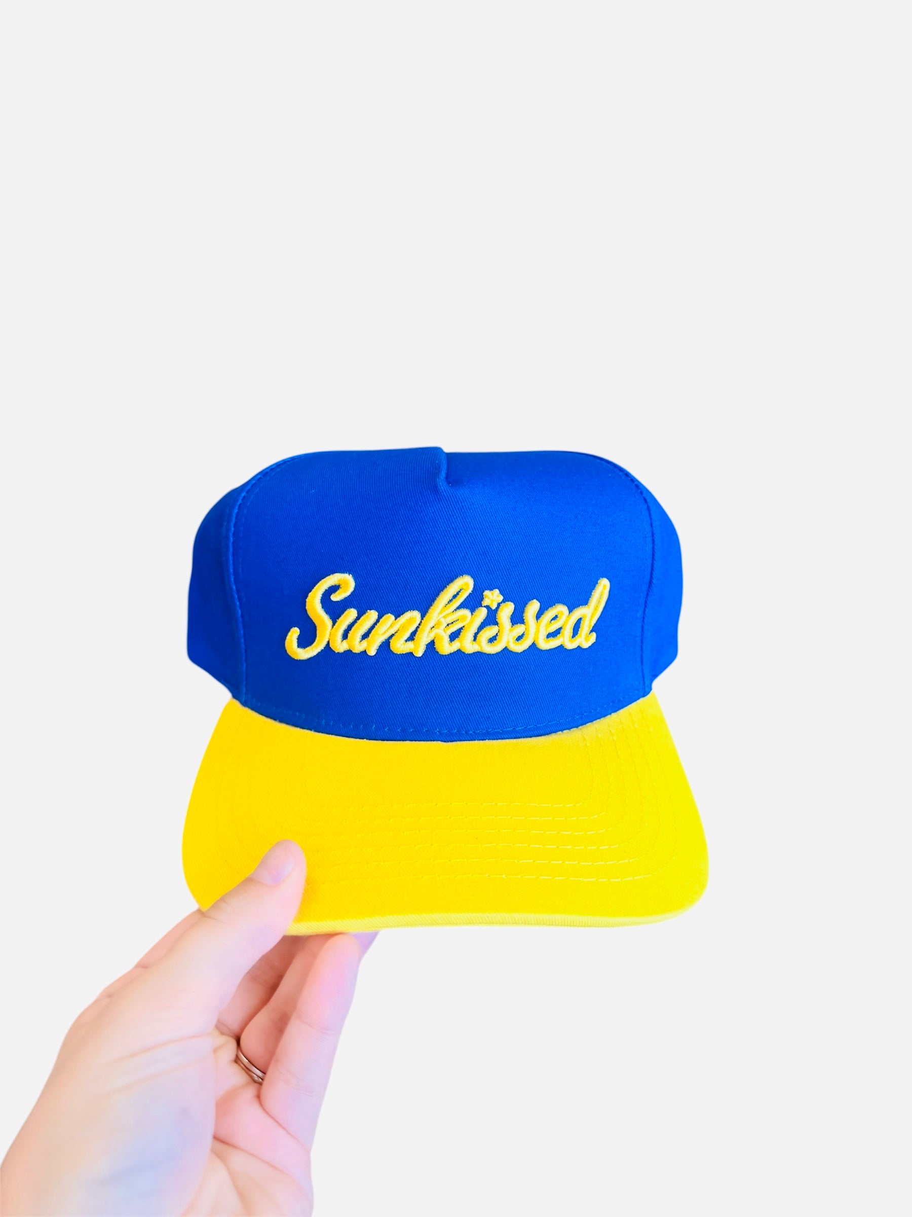 Blue hat with yellow bill and “Sunkissed” embroidered on front, adjustable strap in back