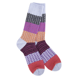 A pair of plush, soft crew socks featuring a patchwork design with various patterns like stripes and chevrons in shades of purple, red, orange, and lavender.
