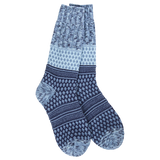 A pair of plush, soft crew socks with a patchwork design featuring various geometric patterns in shades of navy and blue.