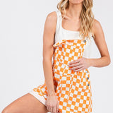 Orange checkered knit romper overalls with cuffed shorts, adjustable straps, and multiple pockets, laid flat to show texture and design.