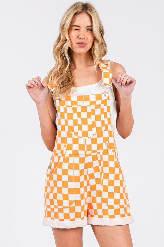 Orange checkered knit romper overalls with cuffed shorts, adjustable straps, and multiple pockets, laid flat to show texture and design.